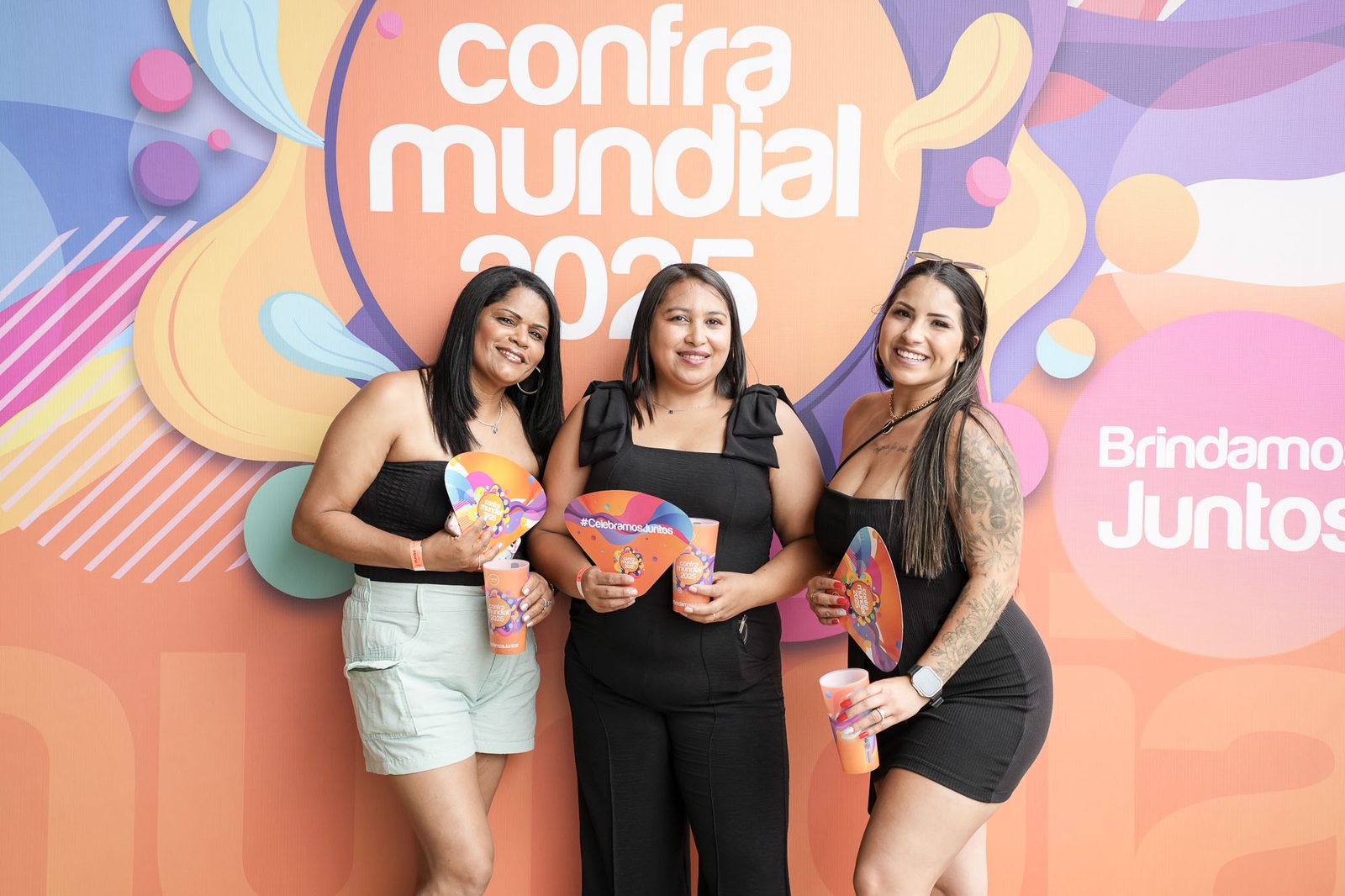 Três convidadas com copos e leques no painel da Confra Mundial 2025