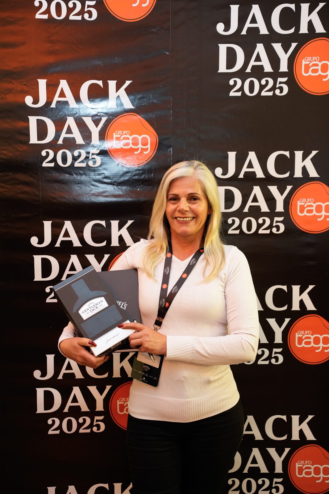 Participante sorrindo com kit Gentleman Jack no backdrop
